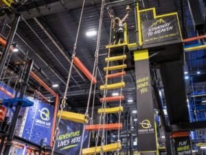 Urban Air Slides, Ninja Course & Ropes Course: Complete Attractions Guide 3 Climber reaching the top platform of the Stairway to Heaven attraction at Urban Air